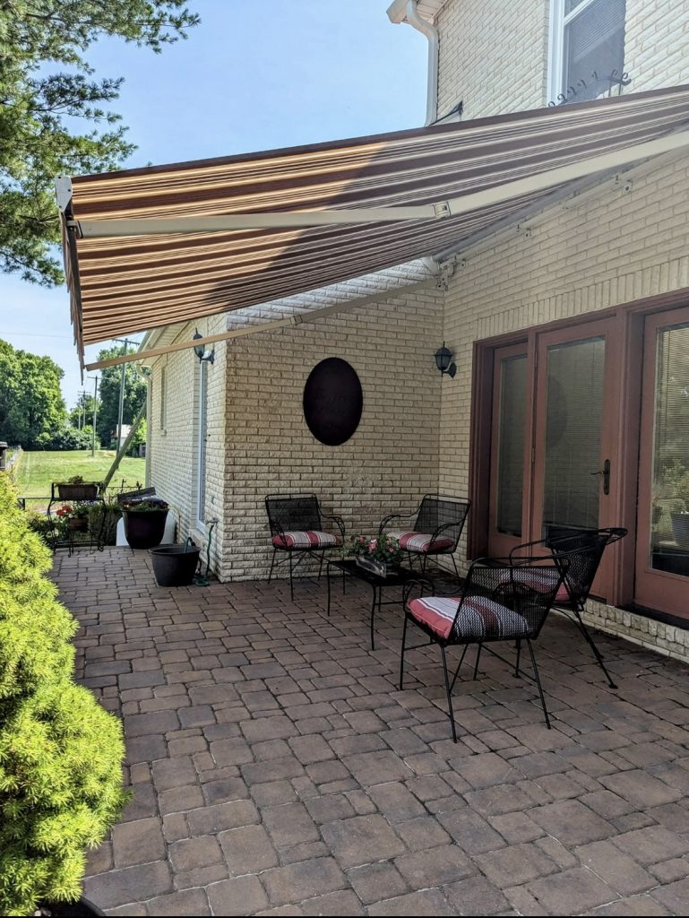 porch with red, yellow, and white awning, and red, white, and black furniture. Home improvements that increase home value