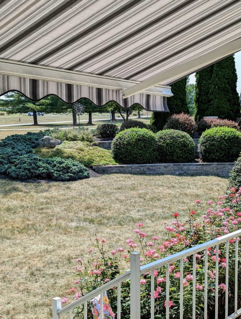 porch leading to a backyard with a black and white striped awning