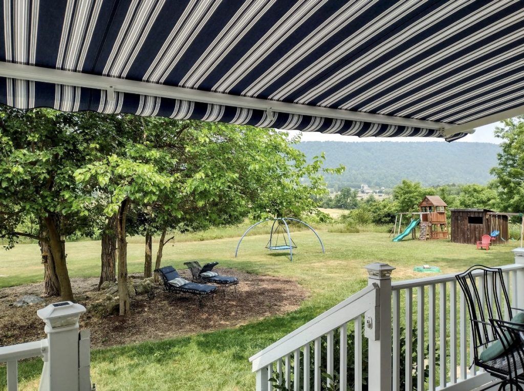 porch leading to a backyard with a blue and white striped awning